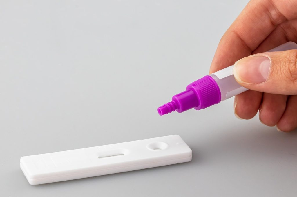 Dłoń trzymająca test ciążowy w trakcie nanoszenia próbki